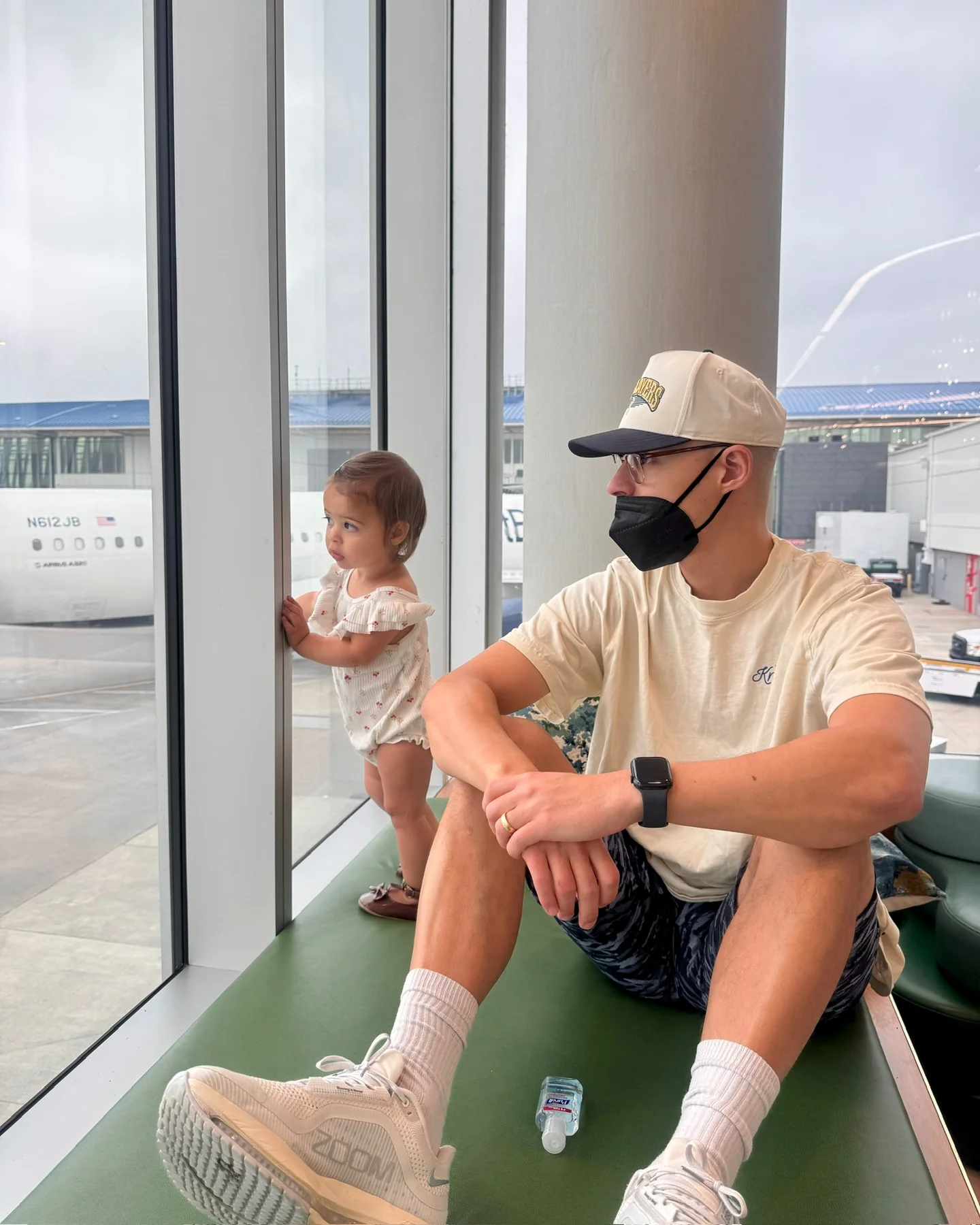 Tyler and Lucia waiting together beside an airport window