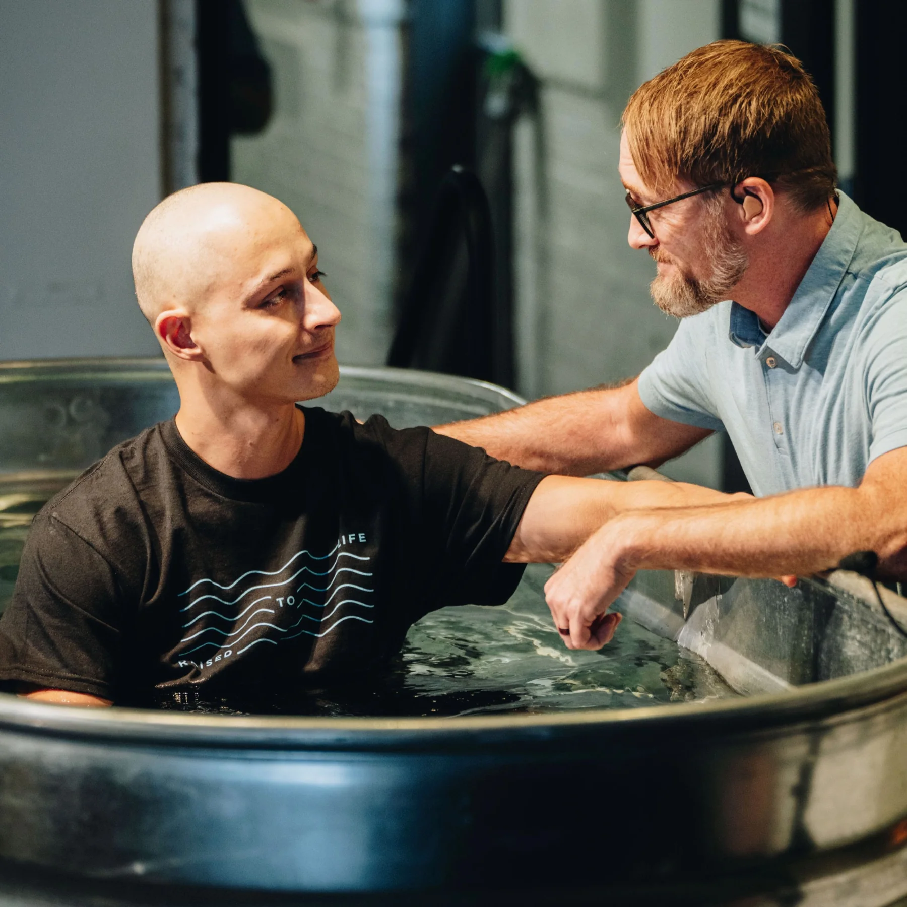 Tyler during his baptism, speaking with a church leader in the baptismal pool