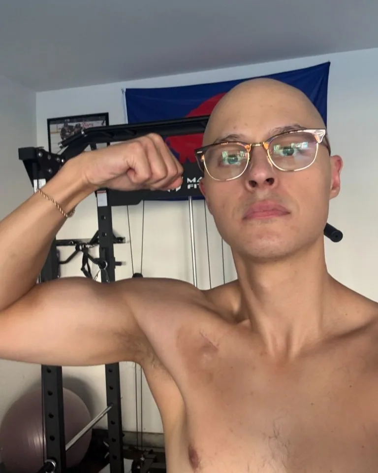 Tyler flexing his arm beside his home workout equipment